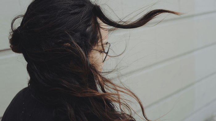 back of person with black hair blowing in the wind