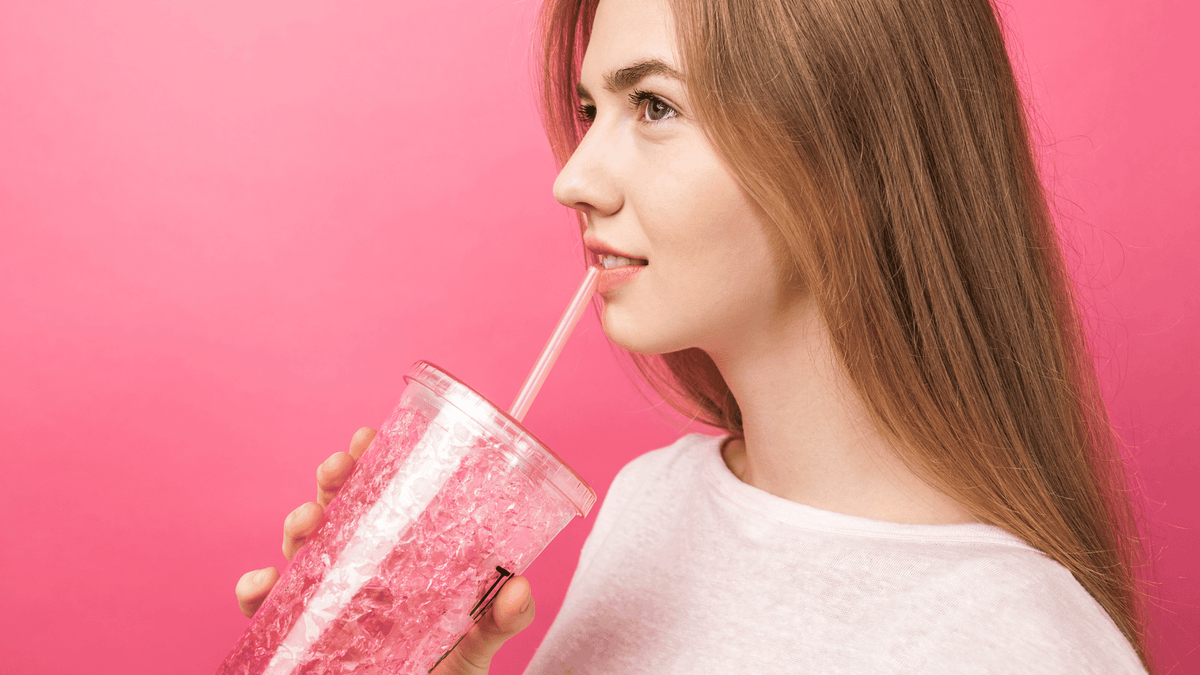 Woman drinking from a pink cup on a pink background