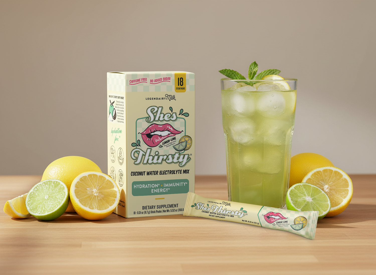 She's Thirsty coconut water electrolyte mix packaging with a glass of lemonade and lemons on a wooden surface.